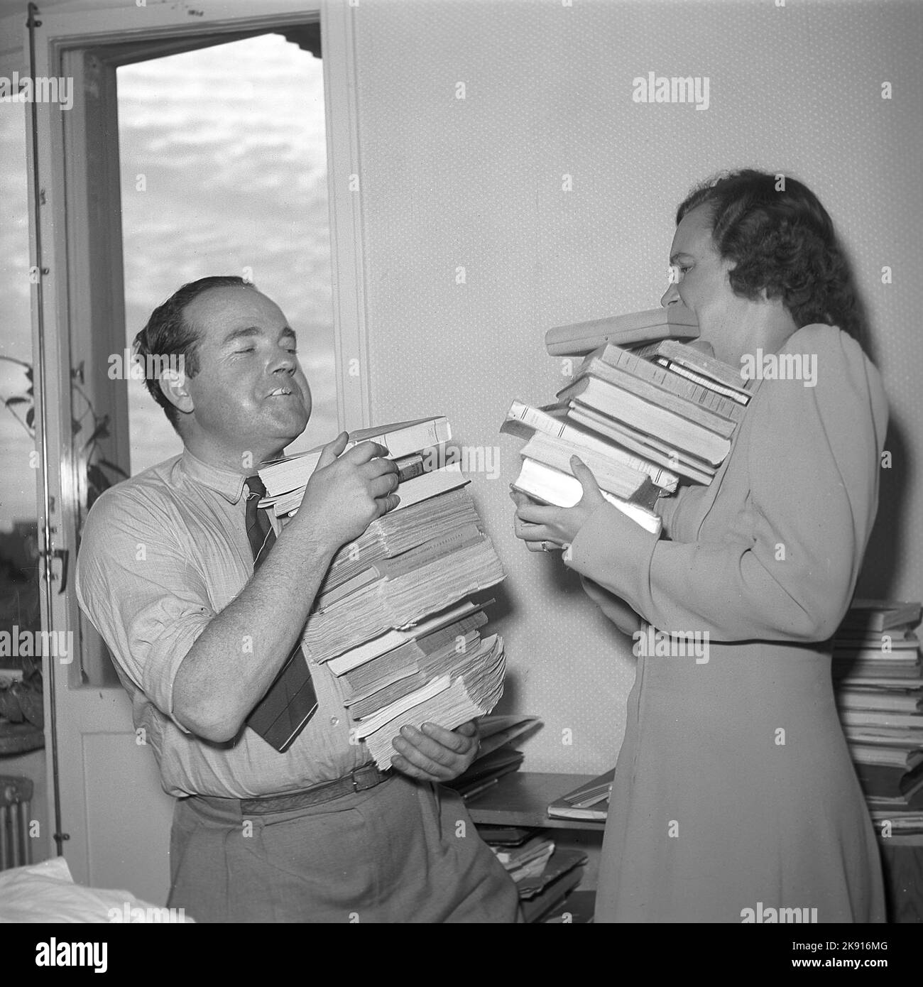 Moving in the 1940s. Actress Inga-Bodil Vetterlund is moving and gets a helping hand by travelbook author Milke. They both are holding as many books as they can. Sweden 1945. Kristofferson ref O140-3 Stock Photo