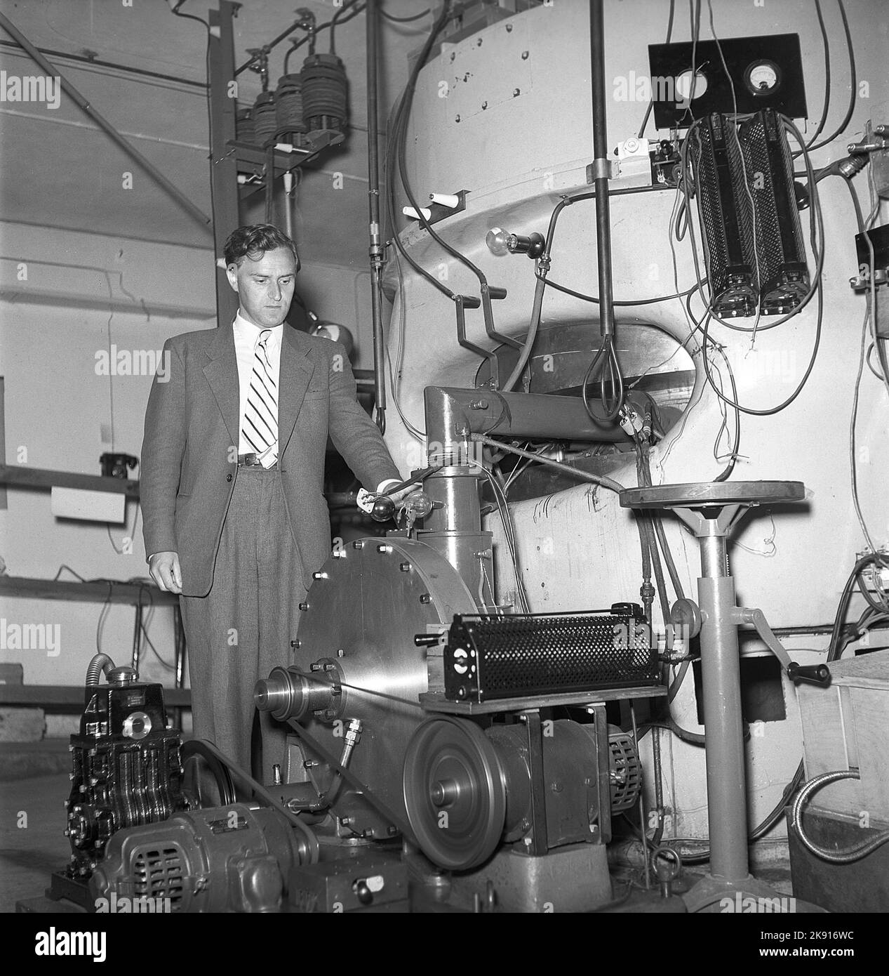 Man and machine in the 1940s. A man is seen in a room with a unusual construction of unknown purpose. Picture taken at KTH Royal institute of Technology. Sweden 1945 Kristoffersson ref P47-5 Stock Photo