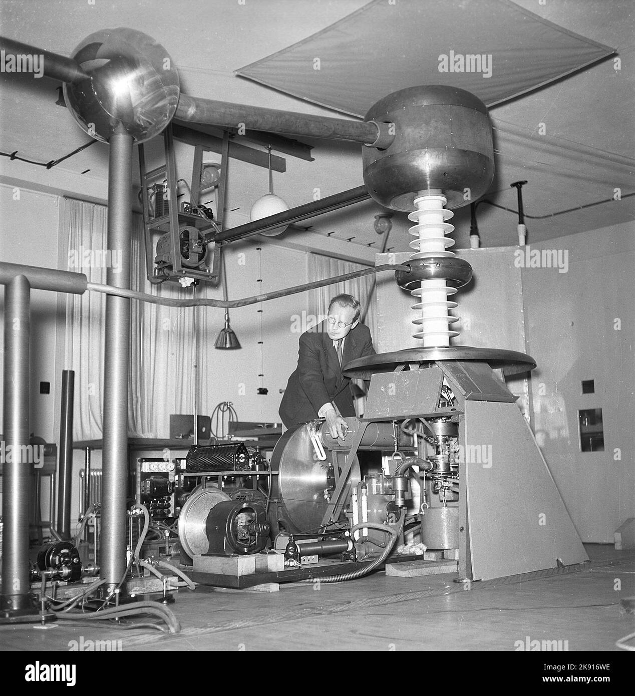 Man and machine in the 1940s. A man is seen in a room with a unusual construction of unknown purpose. Picture taken at KTH Royal institute of Technology. Sweden 1945 Kristoffersson ref P47-4 Stock Photo