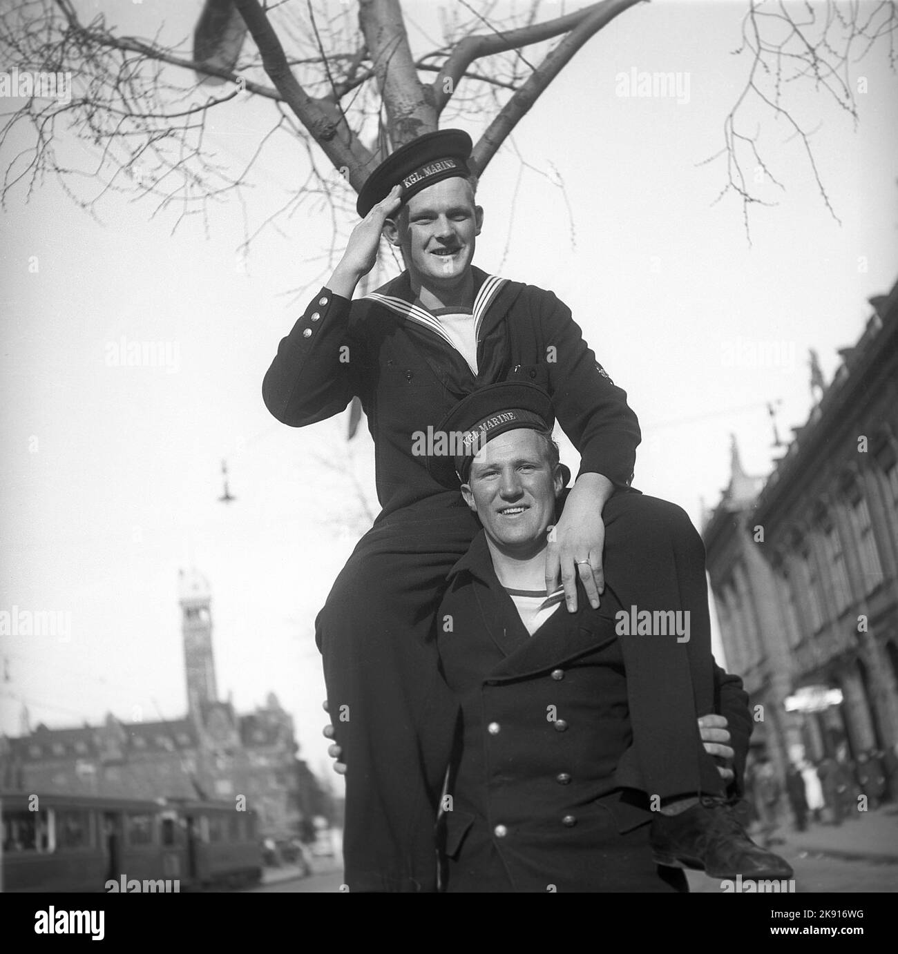 1940s sailors on shore-leave. Two danish seamen looks happy and playful as one sits on his friends shoulders saluting. Denmark Copenhagen 1946 ref T51-1 Stock Photo
