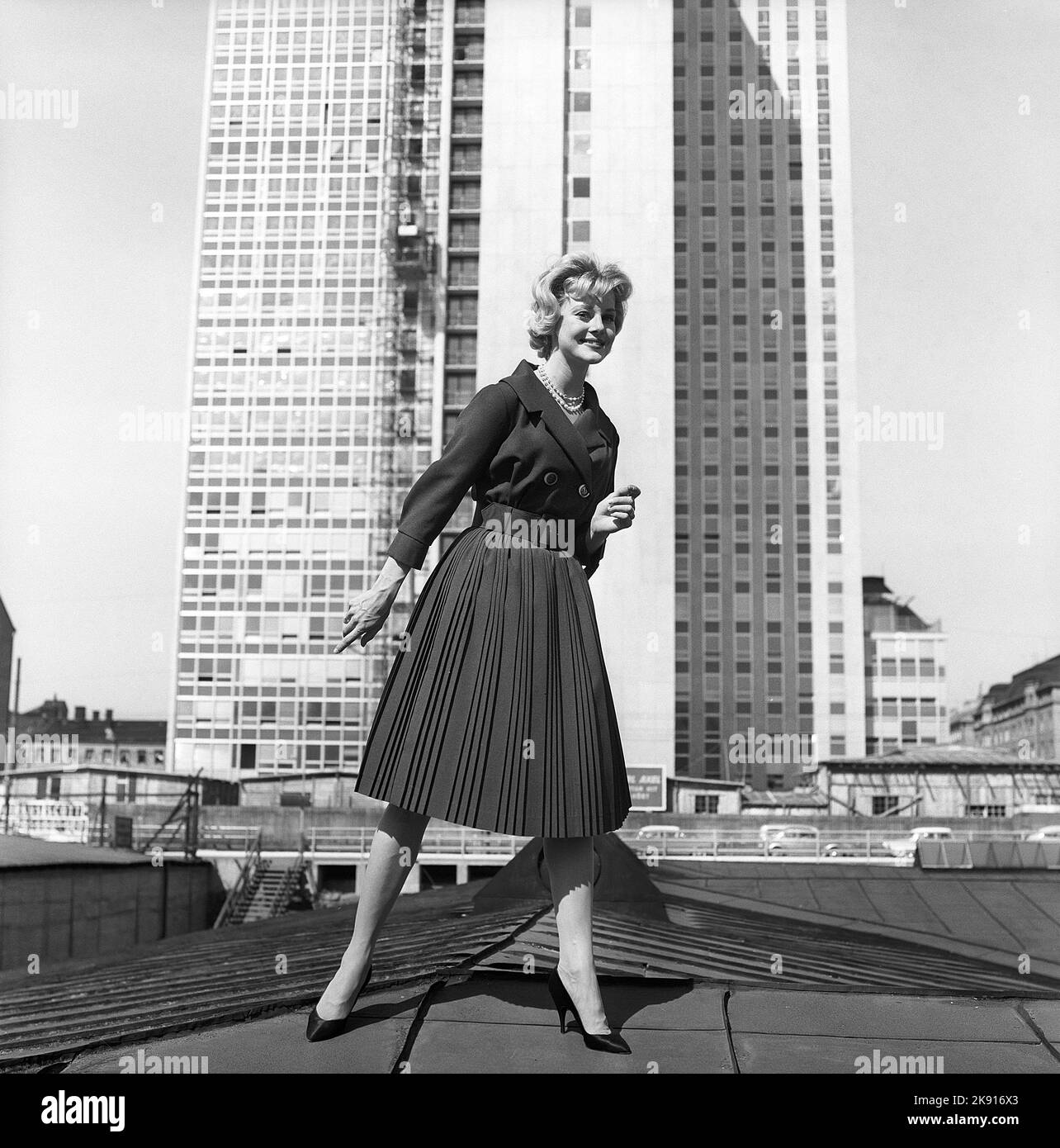 In the 1950s. A woman modelling a 1950s outfit with a jacket and skirt in matching dark. In the background the newly finished skyscraper housing the swedish tax offices. Sweden 1959 Kristoffersson ref CH21 Stock Photo