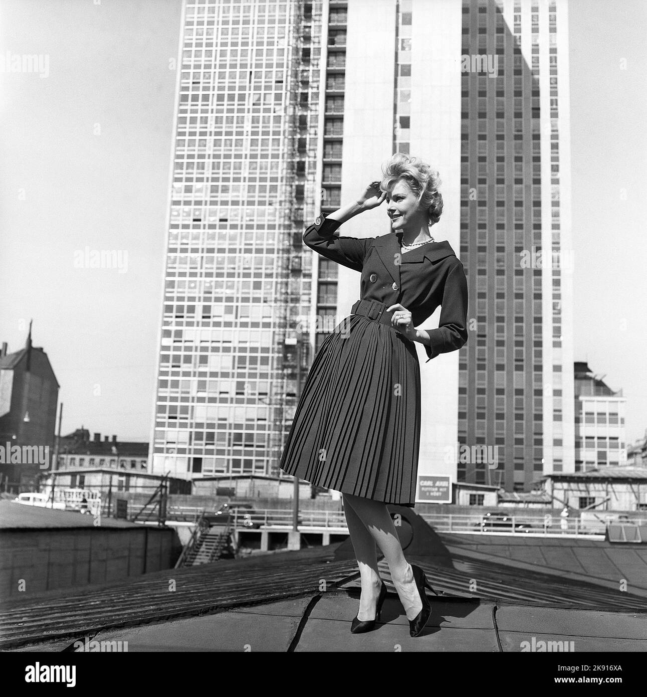 In the 1950s. A woman modelling a 1950s outfit with a jacket and skirt in matching dark. In the background the newly finished skyscraper housing the swedish tax offices. Sweden 1959 Kristoffersson ref CH21 Stock Photo