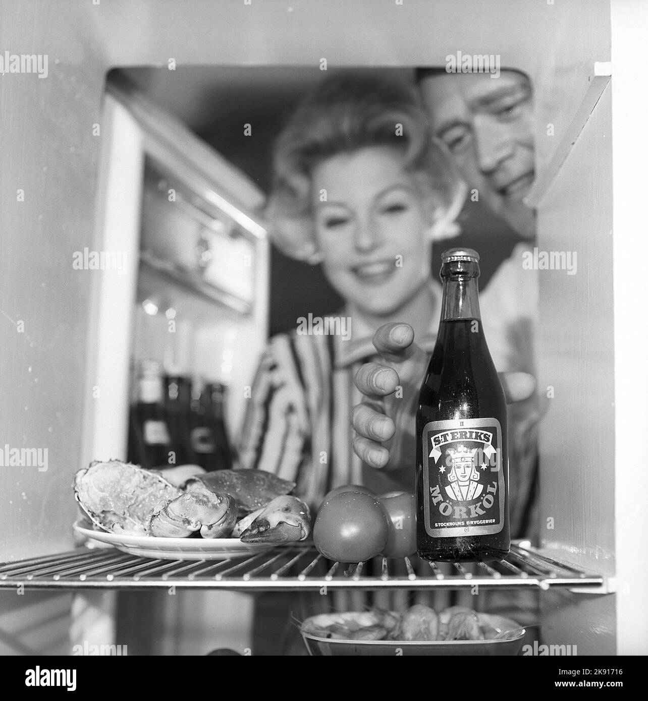 In the kitchen 1950s. A couple in their kitchen and at the refrigerator where the food and beer is kept.  Sweden 1959. Kristoffersson ref CH73-6 Stock Photo