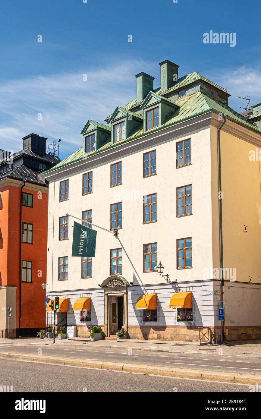 Sweden, Stockholm - July 17, 2022: Priority Group white office building on Skeppsbron quay. Business consultants. Green flag and orange awnings. Stock Photo
