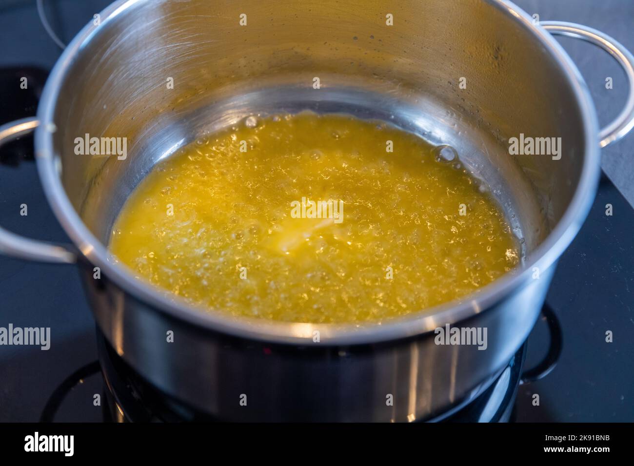 Melting butter in a stainless steel saucepan on the black stove, cooking concept, selected focus Stock Photo