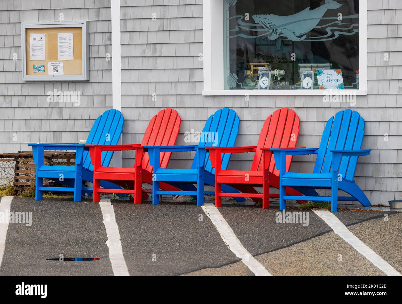 Plymouth, Massachusetts, USA - September 12, 2022: Red and blue chairs sit in front of a place of business on the waterfront. Stock Photo