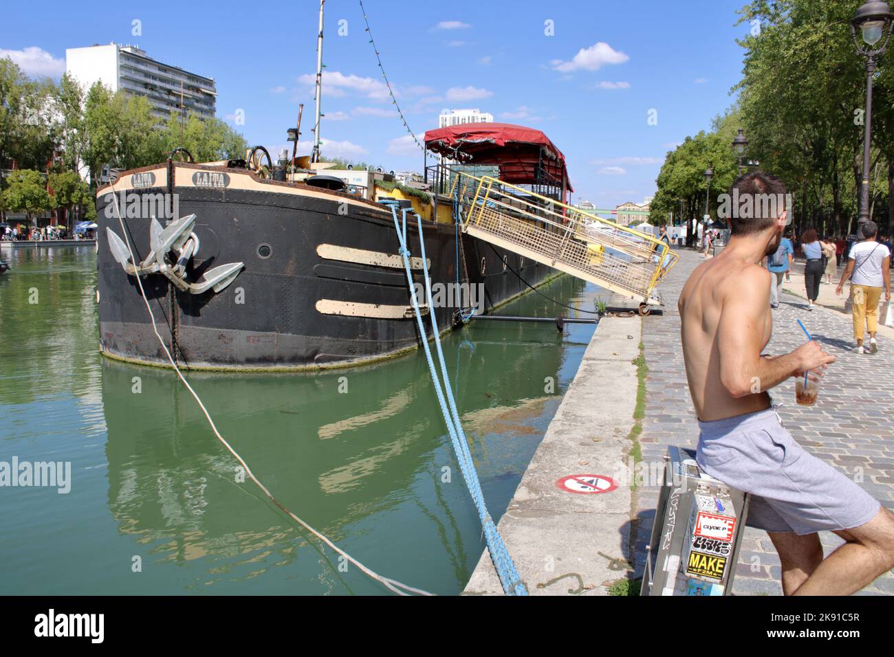 View of a boat and people relaxing along the Bassin de la Villette at Paris-Plage in the 19th arrondissement of Paris France. Stock Photo