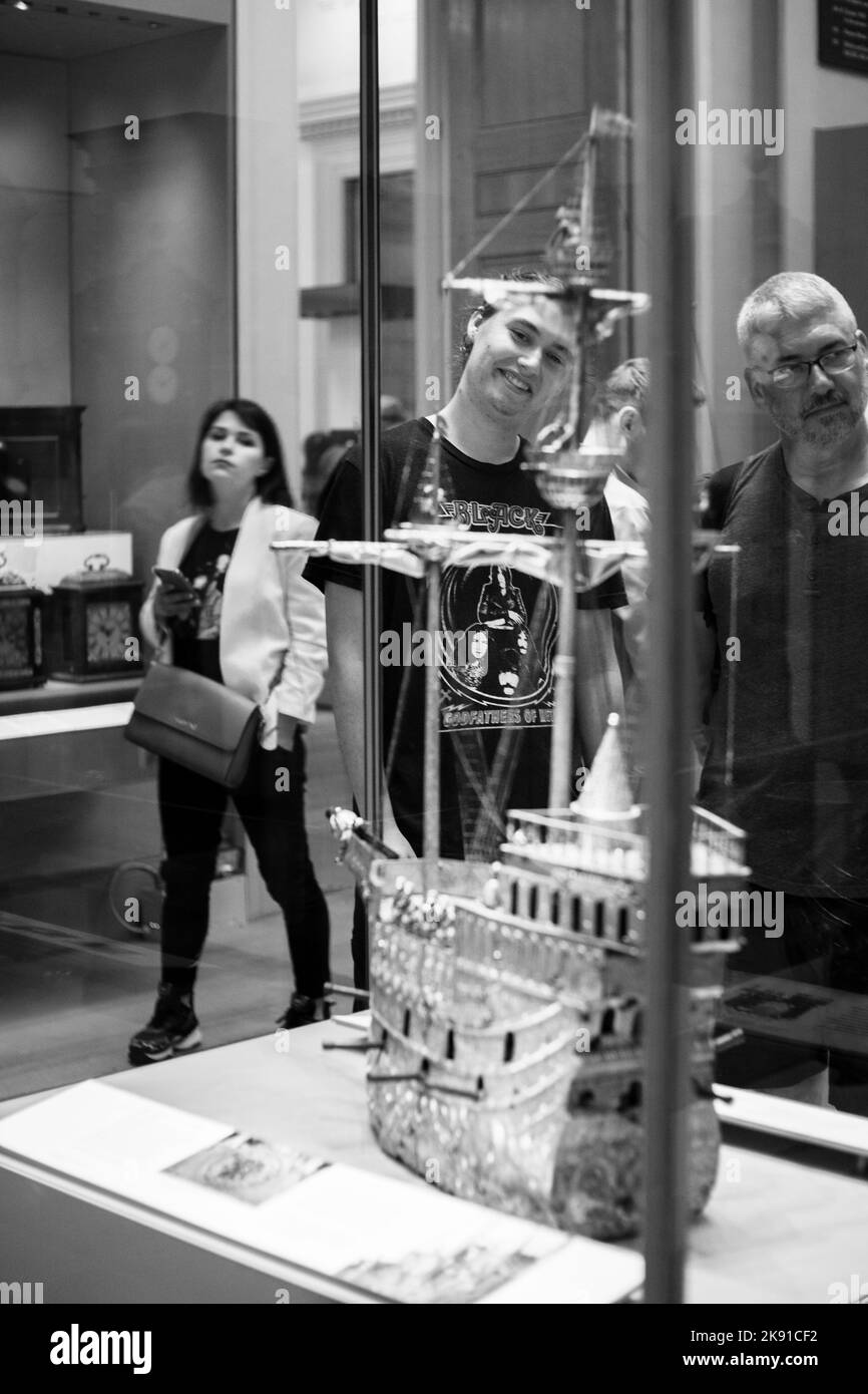 A grayscale shot of a Man looking at a golden ship at the British museum, London Stock Photo