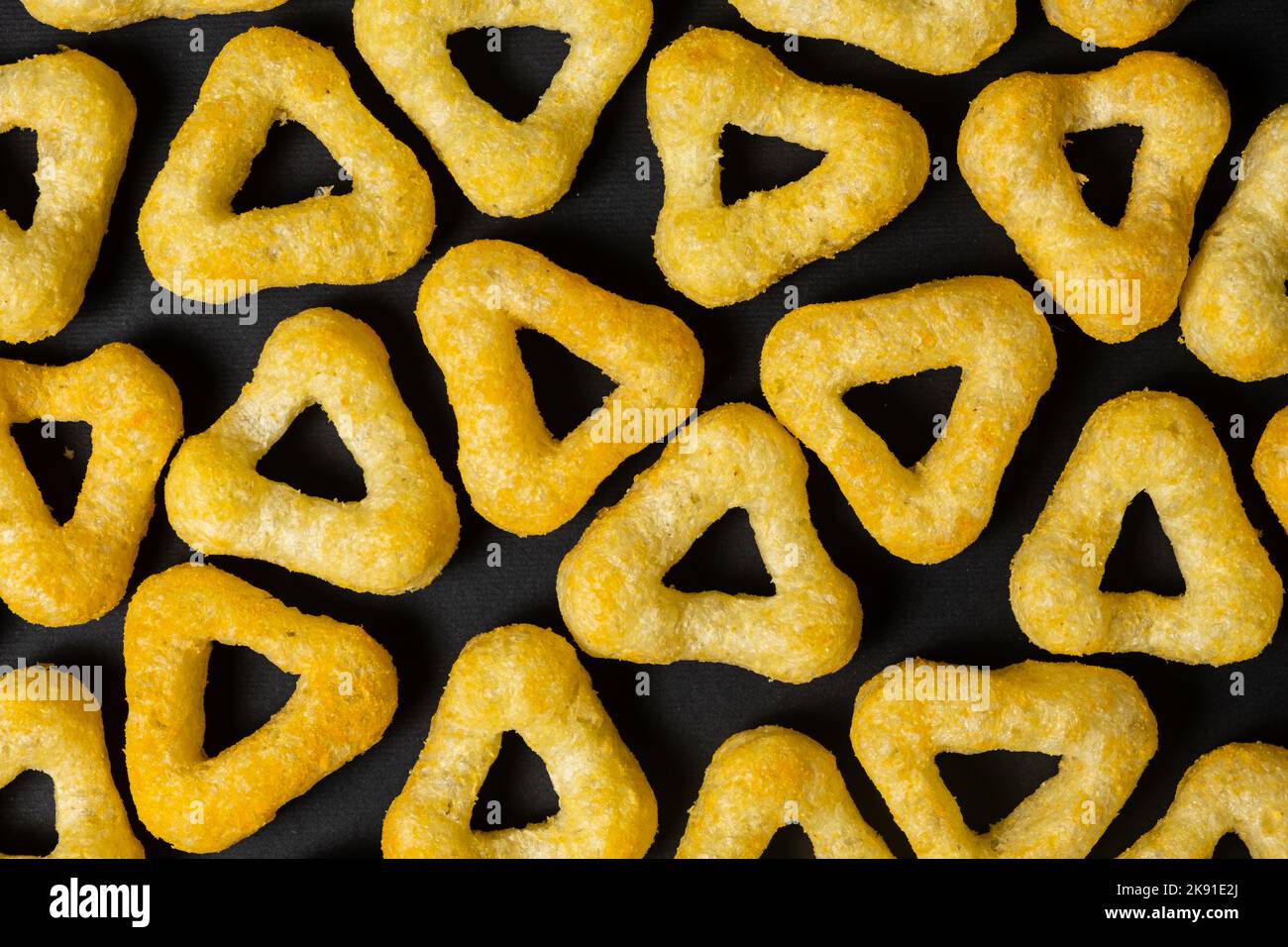 Delicious crispy corn chips triangular shape with spices on a black
