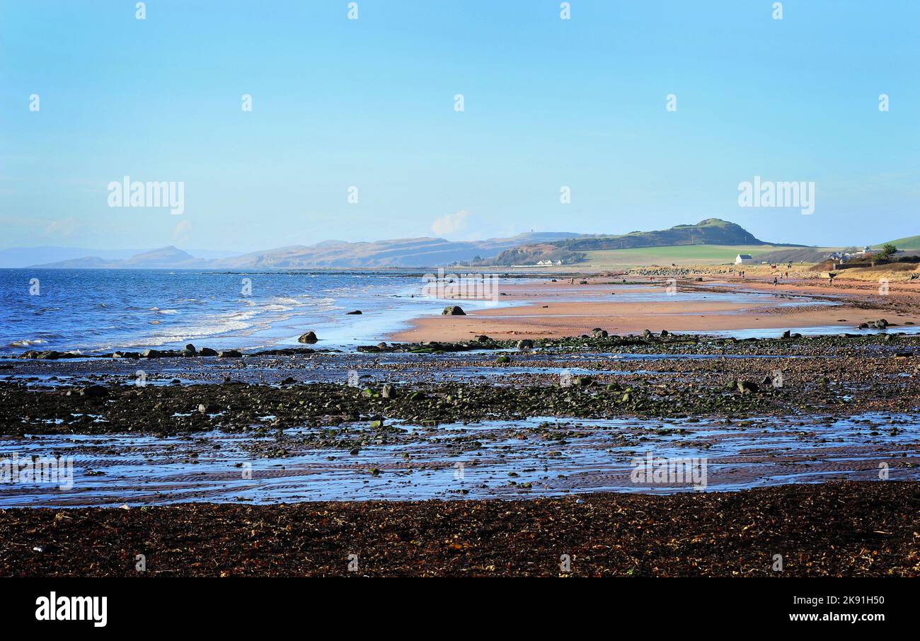 A view of the sea waves reaching the sandy shore of Seamill village under the blue sky Stock Photo