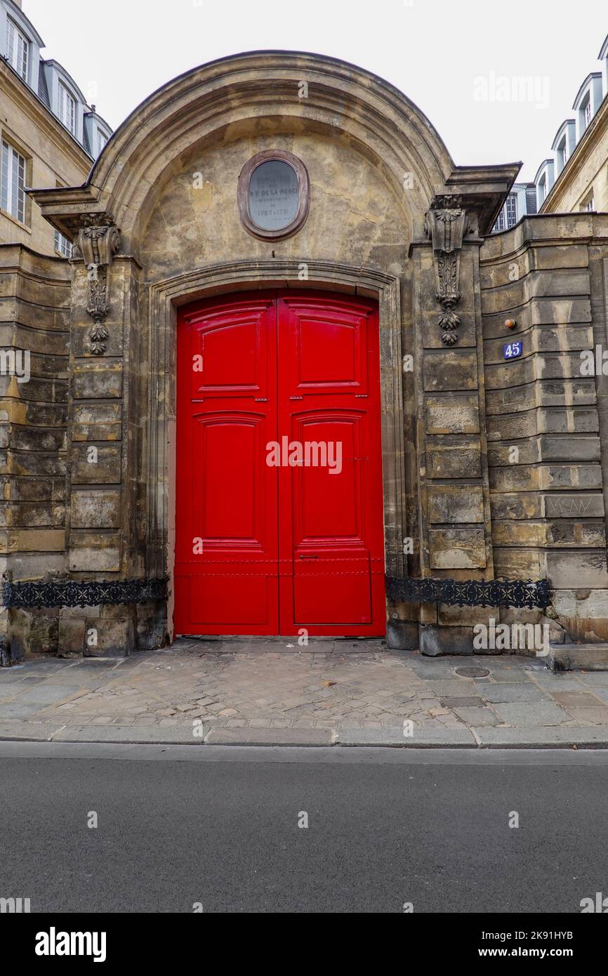Bright red double doors at entry to ancient, 17th century building at 45 rue des archives, Paris, France. Stock Photo