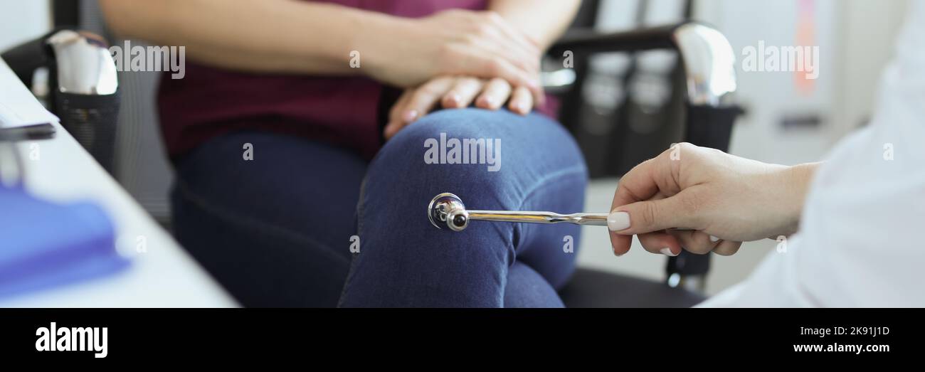 Doctor neurologist checking knee reflexes of female patient with