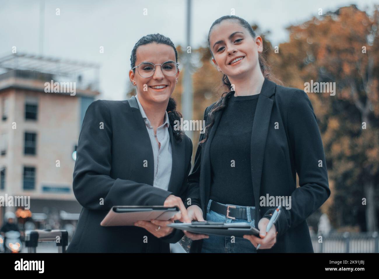 The two attractive caucasian girls in a formal style in the street ...