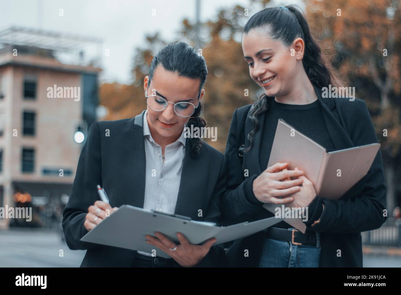 The two attractive caucasian girls in a formal style in the street ...