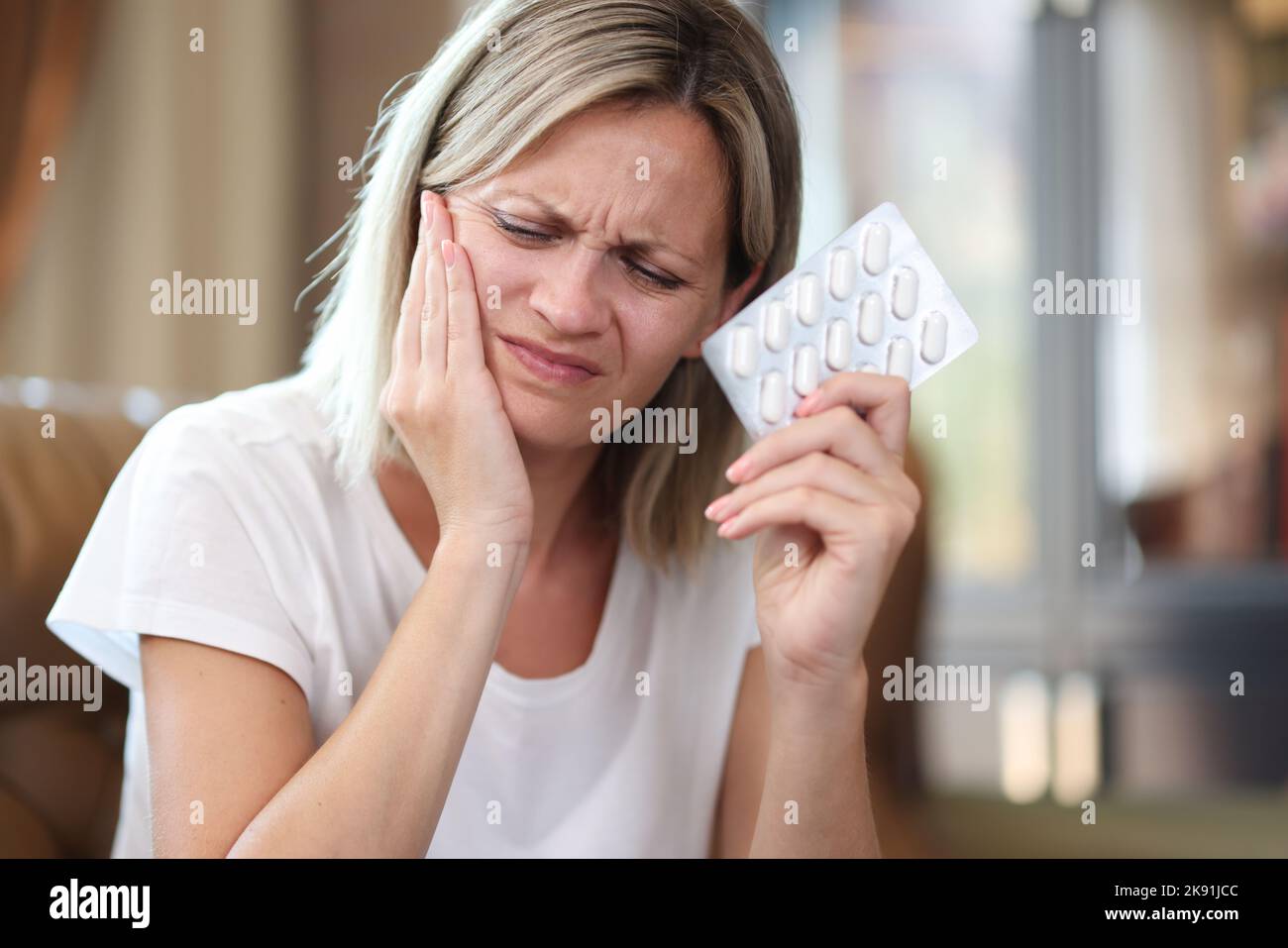 Young woman suffering from tooth pain and holding blister of pills Stock Photo