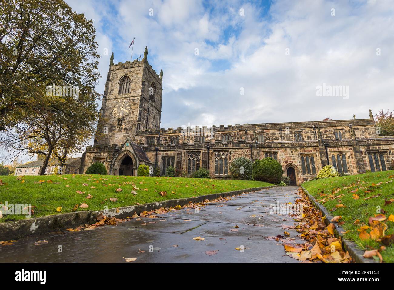 Leaves line a pathway towards the Holy Trinity Church in Skipton, Yorkshire seen in October 2022. Stock Photo