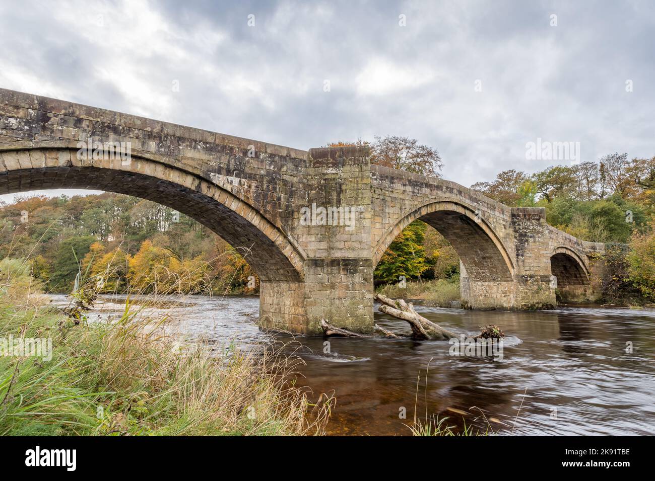 The fast flowing River Wharfe passes under Barden Bridge in the heart of the Yorkshire Dales pictured in the autumn of 2022. Stock Photo