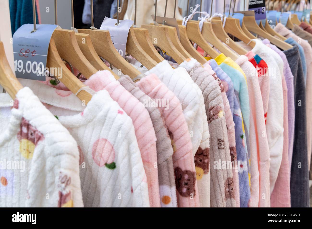 Crowded clearance section in a clothing store, with various colorful  garments placed tightly on racks in no particular order; fast fashion  concept Stock Photo