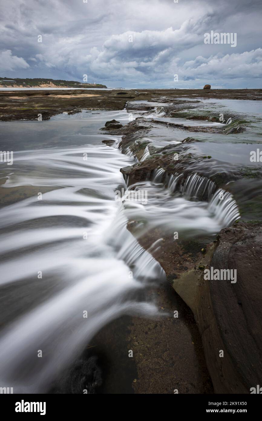 A vertical shot of cascading flowing water near the Norah Head Lighthouse from Soldiers Point Stock Photo