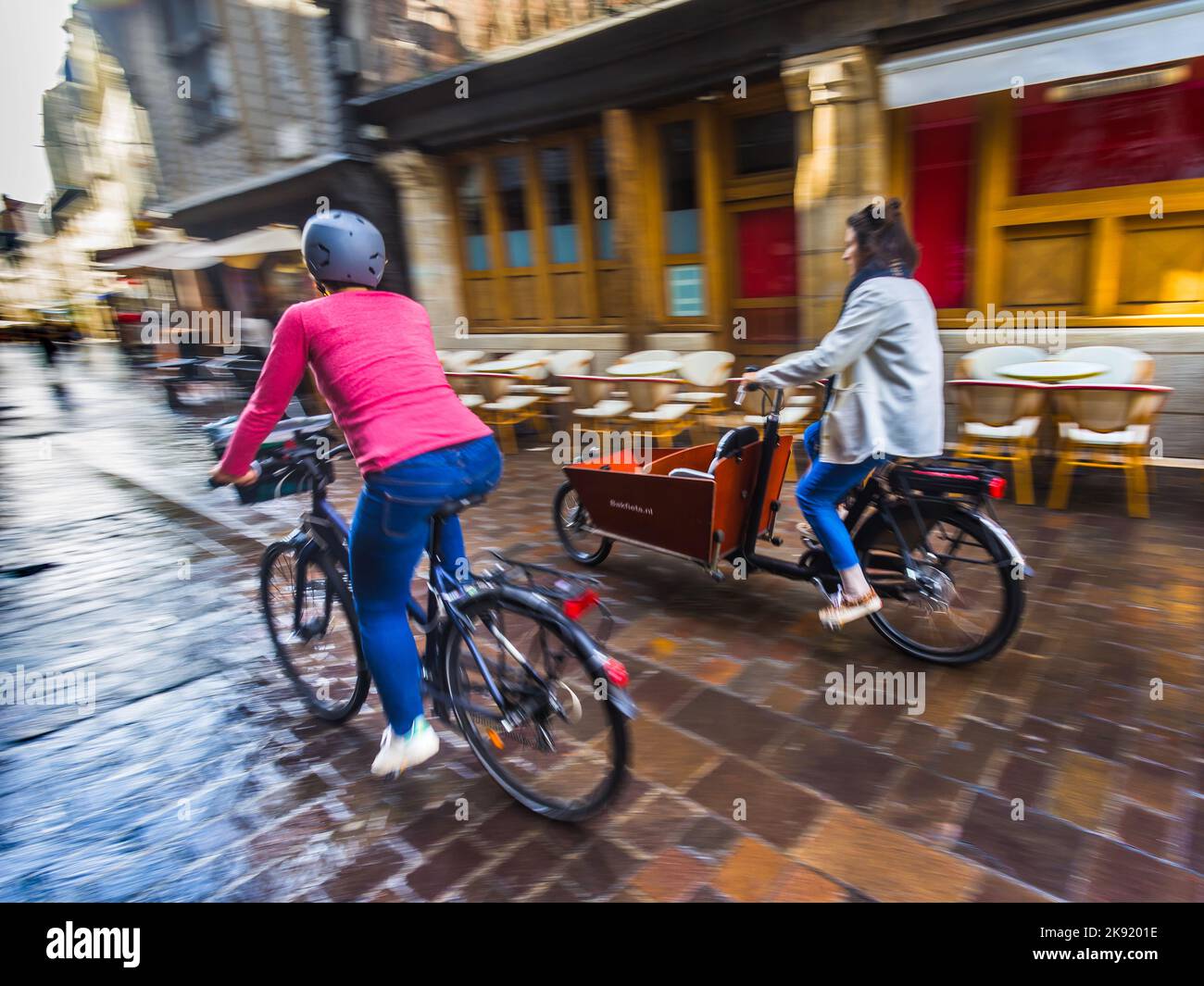 Two women on bicycles cycling through the old quarter of Tours, Indre-et-Loire (37), France. Stock Photo