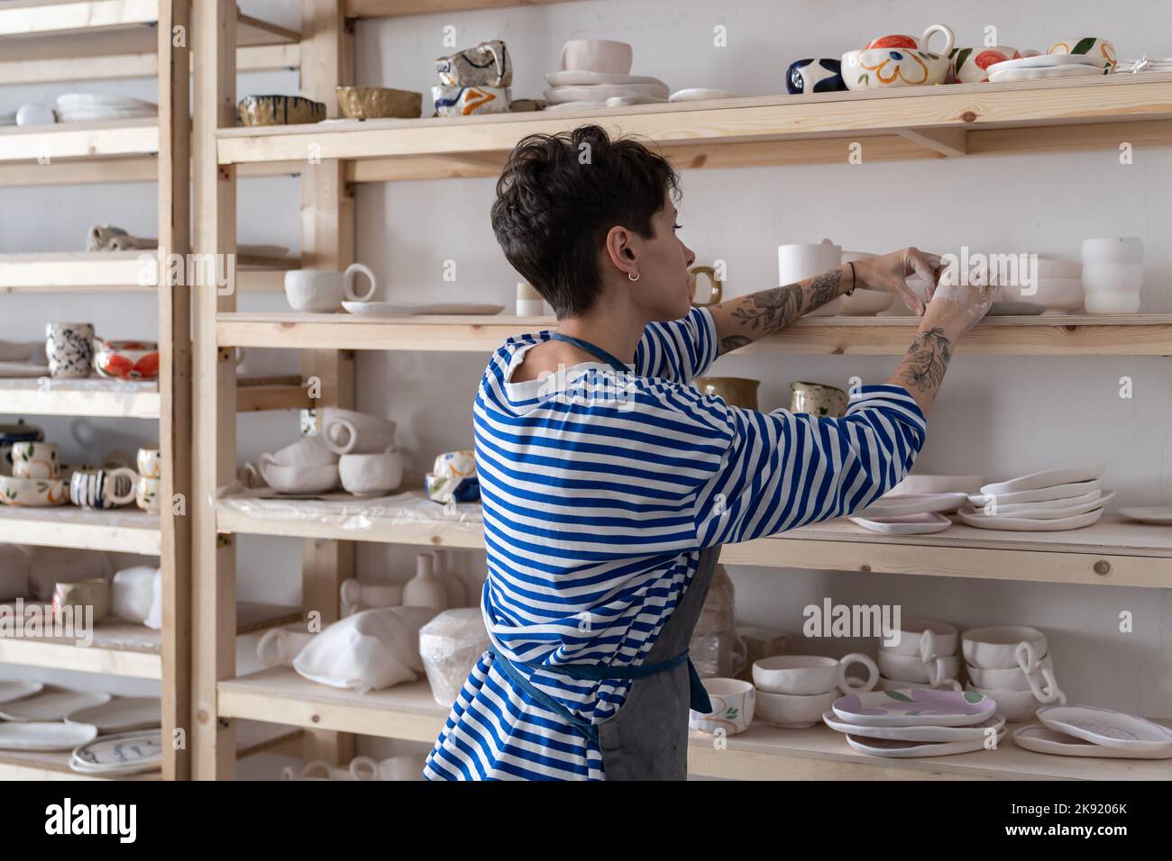 Pottery artist placing clay objects on shelves to dry before firing