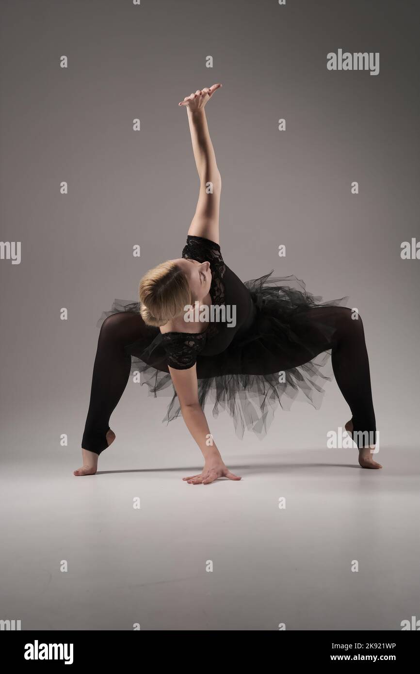Ballerina Dancing with tutu Modern Ballet Dancer in dancer tutu, Gray Background. Dancer in Black clothes showing her flexibility posing on gray Stock Photo