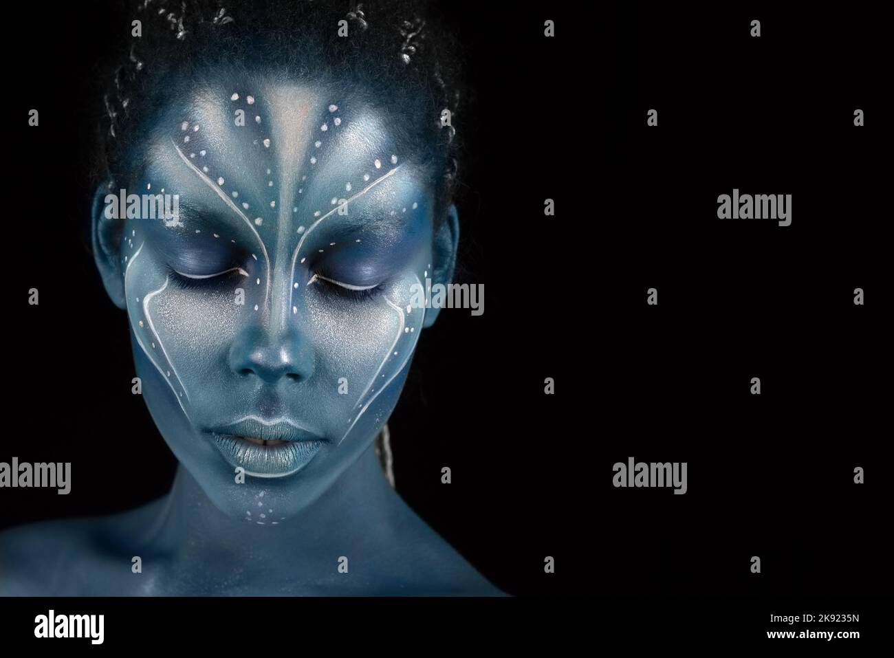 Portrait of beautiful African girl with blue tribal paintings resembling na'vi tribe in Avatar movie. Extraterrestrial concept Stock Photo