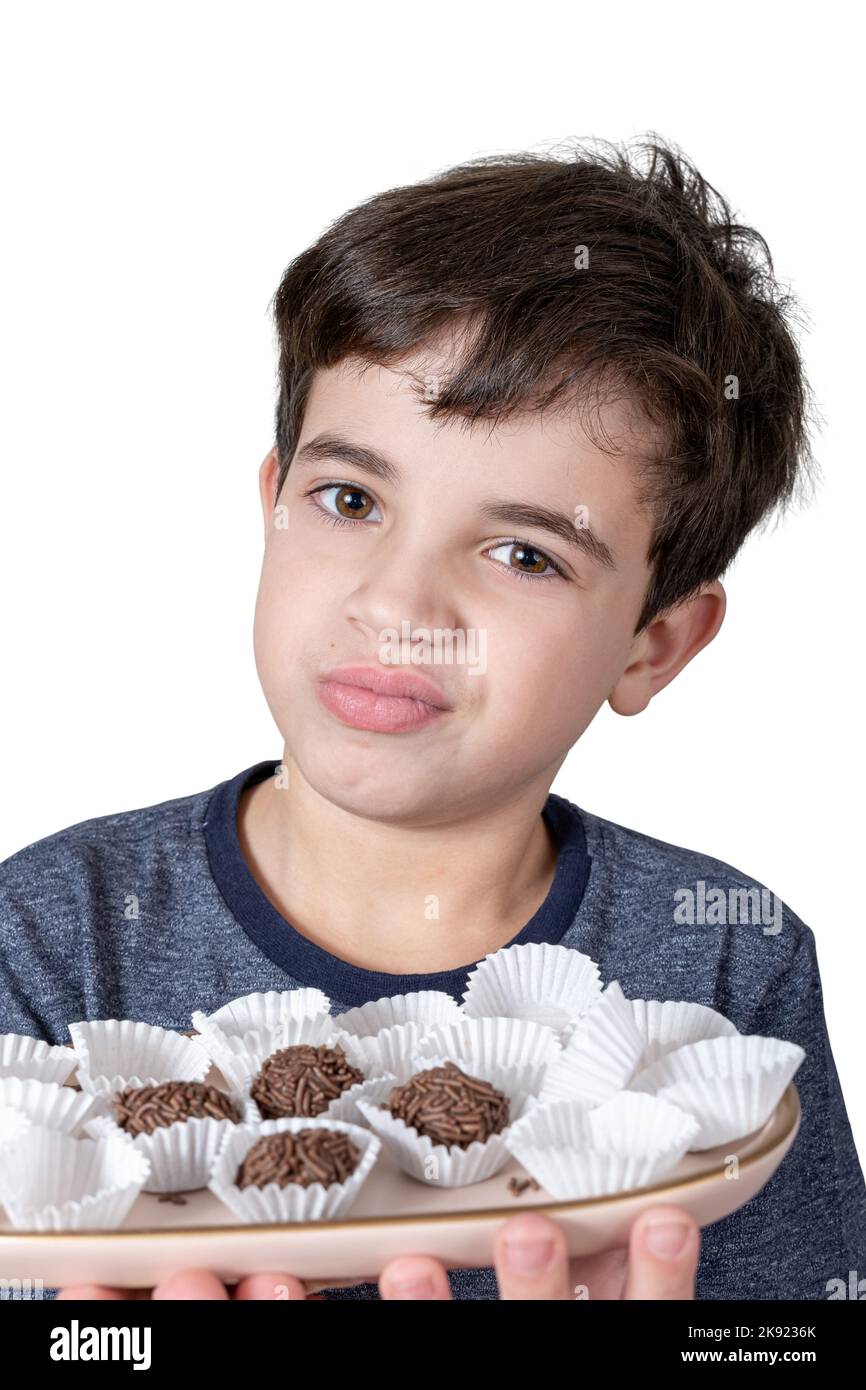 9 year old child holding a tray with Brazilian fudge balls and making a doubtful face Stock