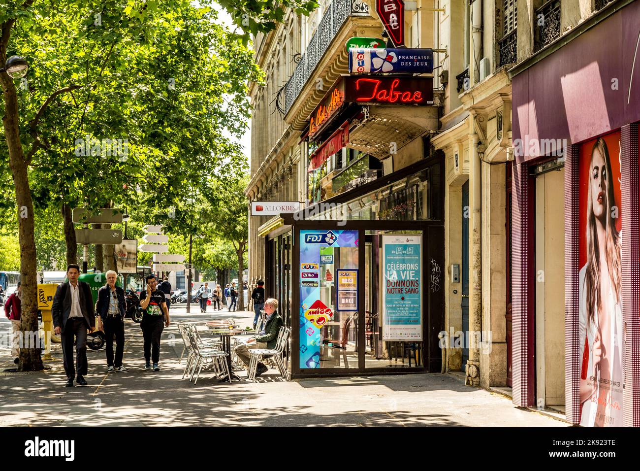 PARIS, FRANCE - JUNE 9, 2015: man sitting in a typical bar with tabac shop and winter gardenn at the sidewalk. It is typical for paris that all bars h Stock Photo