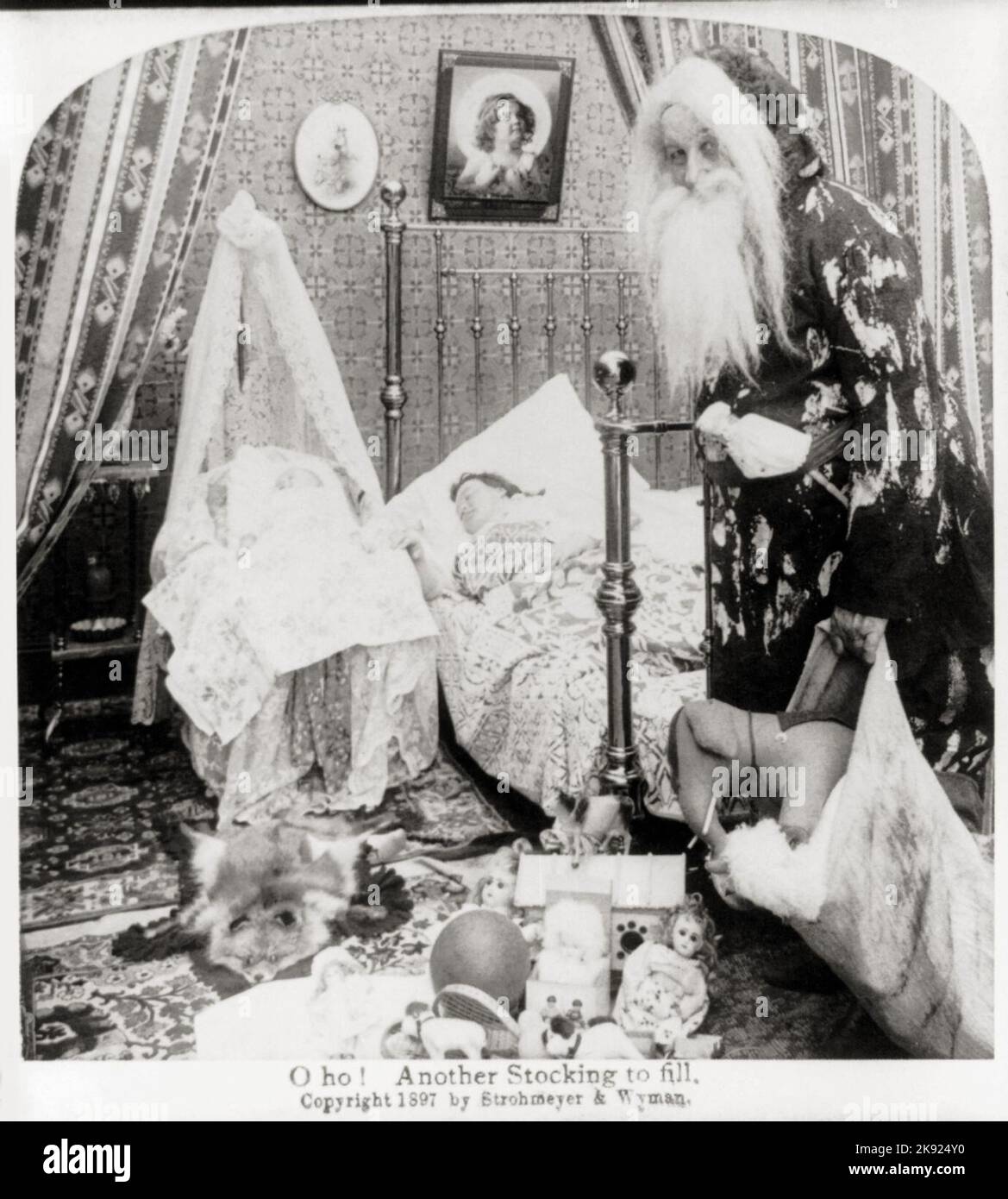 O ho! Another stocking to fill - A classic Santa Claus finds baby in cradle. 1897 Stock Photo