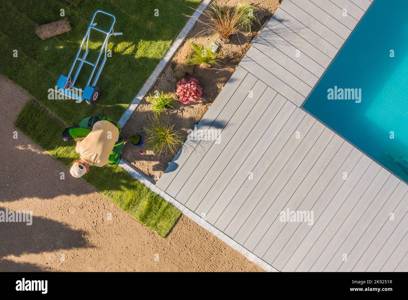 Professional Landscaper Installing Roll Out Lawn Around Outdoor Swimming Pool. Residential Backyard Garden Landscaping Work in Progress. Aerial View Stock Photo