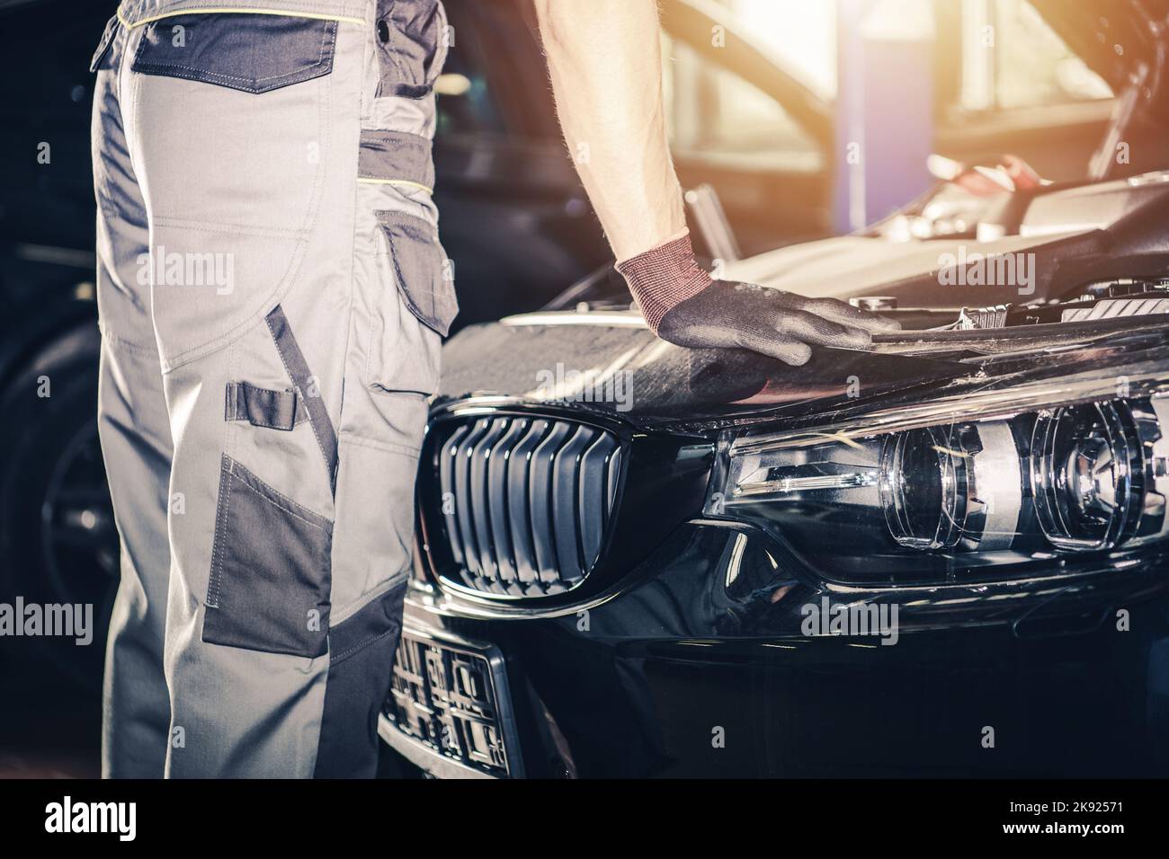 Professional Vehicle Mechanic in White Uniform and Gloves Looking Under