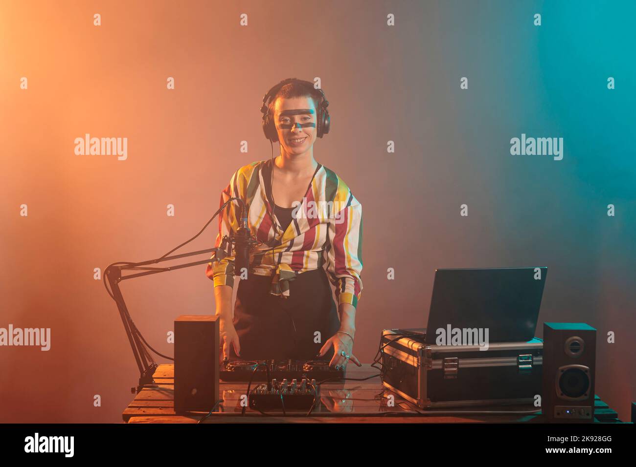 Cool artist mixing tunes at turntables, using dj audio instrument and