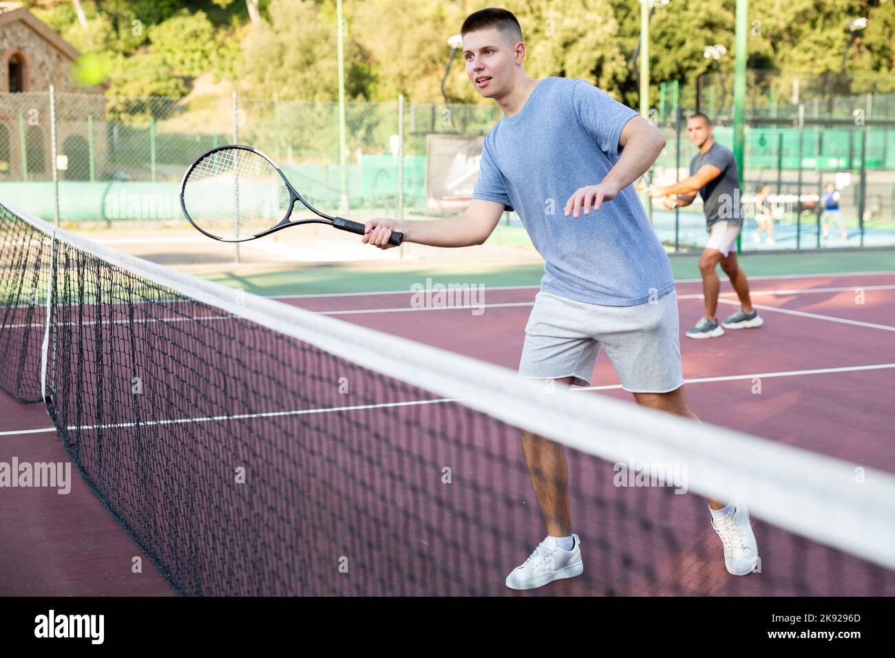 Young teenage player training on court. Boy using racket to hit ball ...