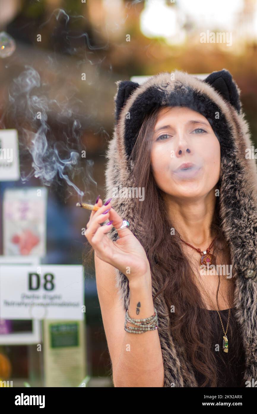 A young woman in a Halloween hat smokes a hemp flower (Cannabis sativa) joint, which is legal in NC, USA Stock Photo