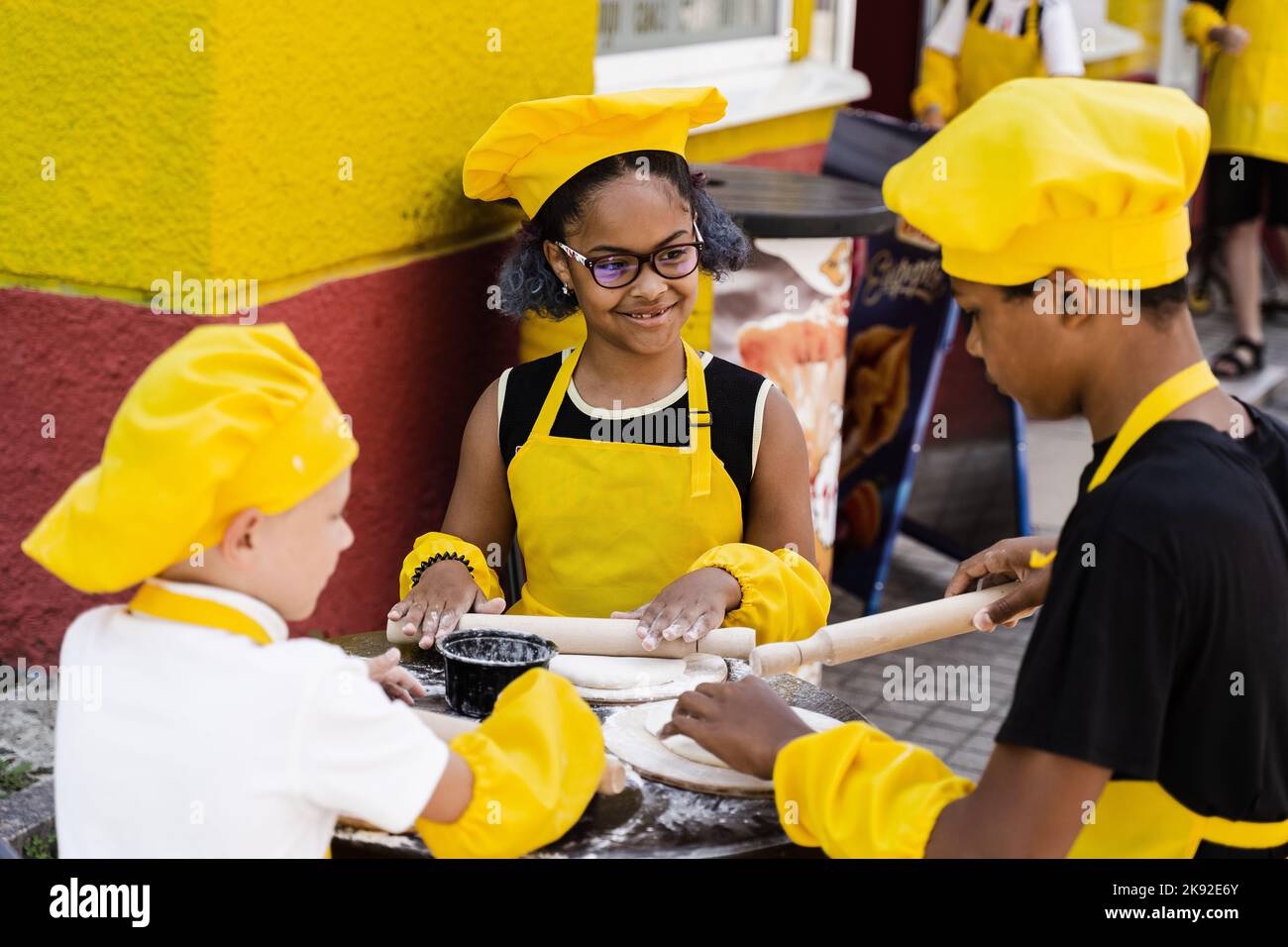 Multinational company of children cooks in yellow uniforms cooking