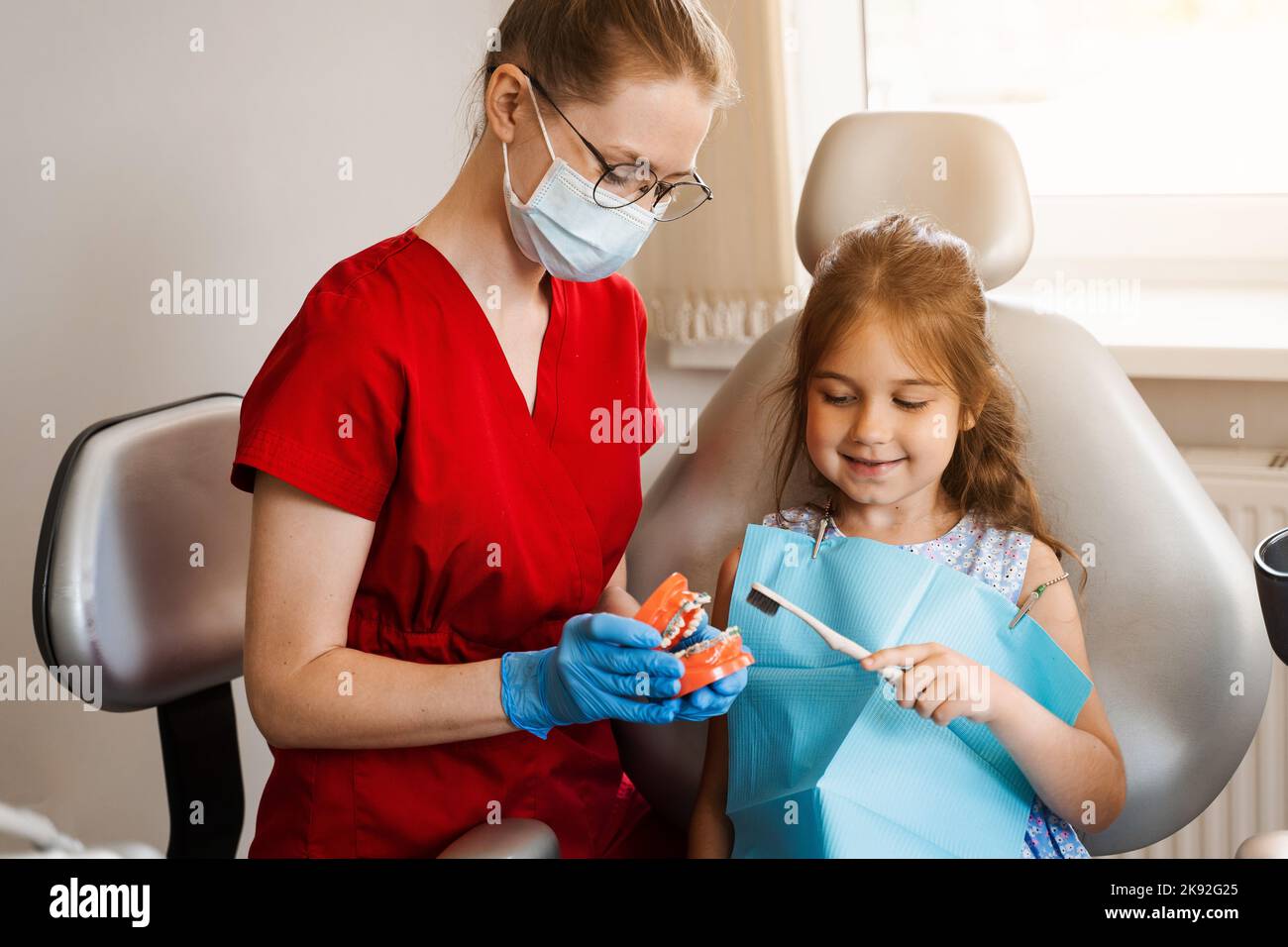 Pediatric dentist teaching oral hygiene lesson for kids in dentistry