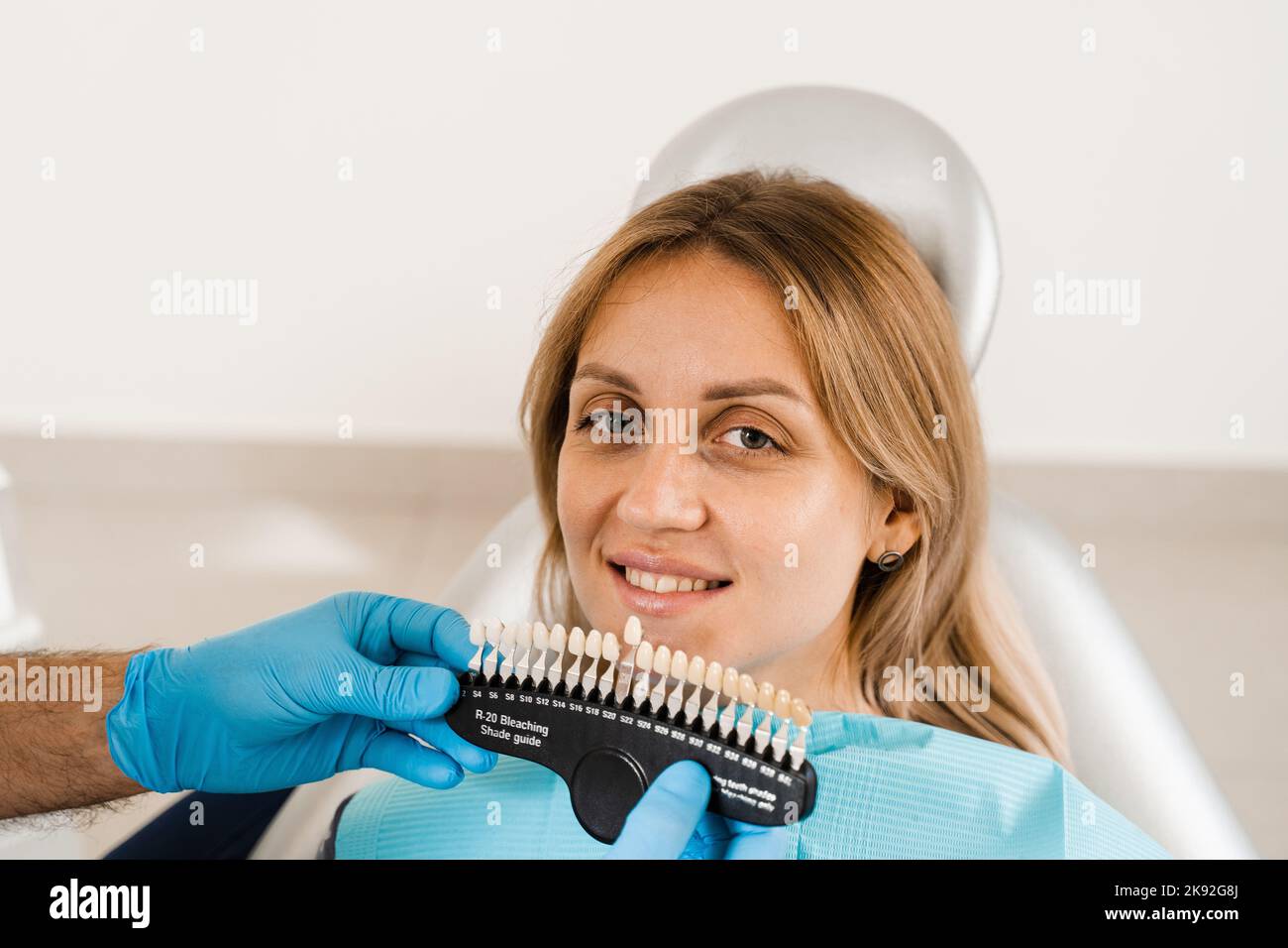 Tooth whitening. Dentist working with teeth color shades guide