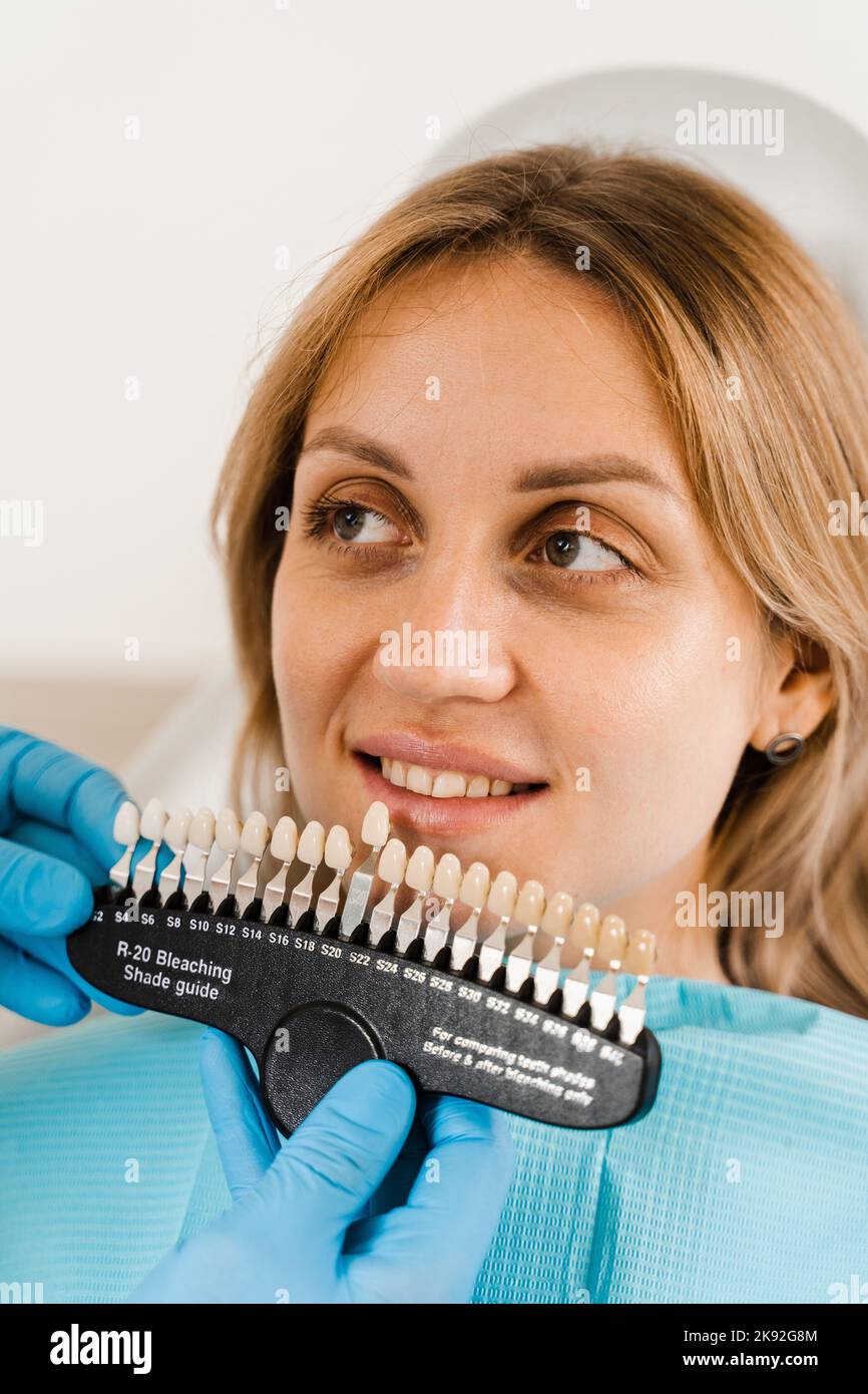 Teeth color shades guide with woman patient. Tooth whitening. Dentist