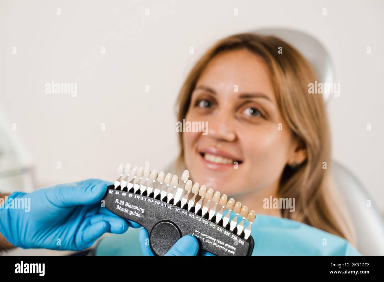 Teeth color shades guide with woman patient. Tooth whitening. Dentist