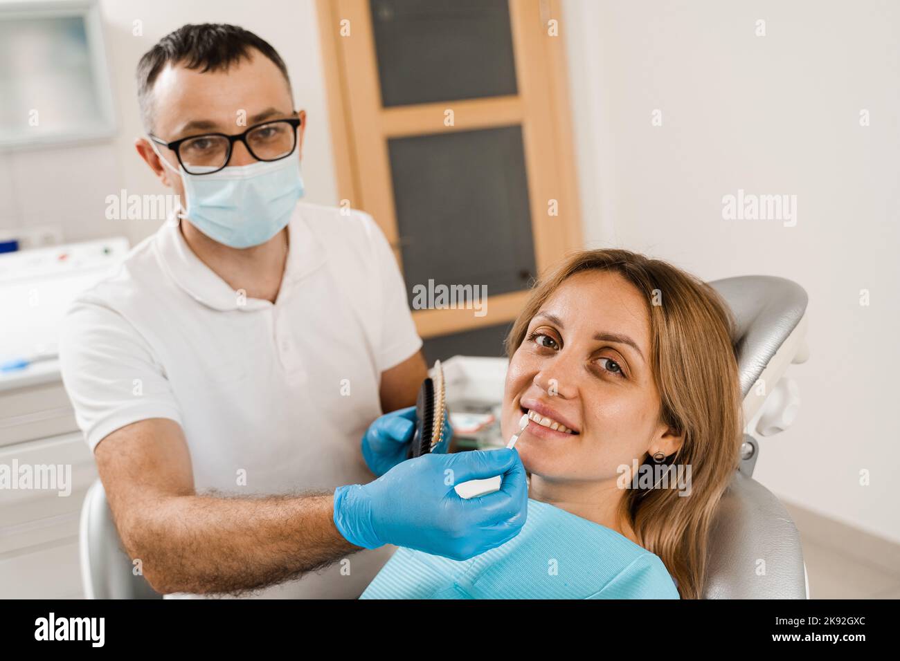 Tooth whitening. Dentist working with teeth color shades guide. Patient