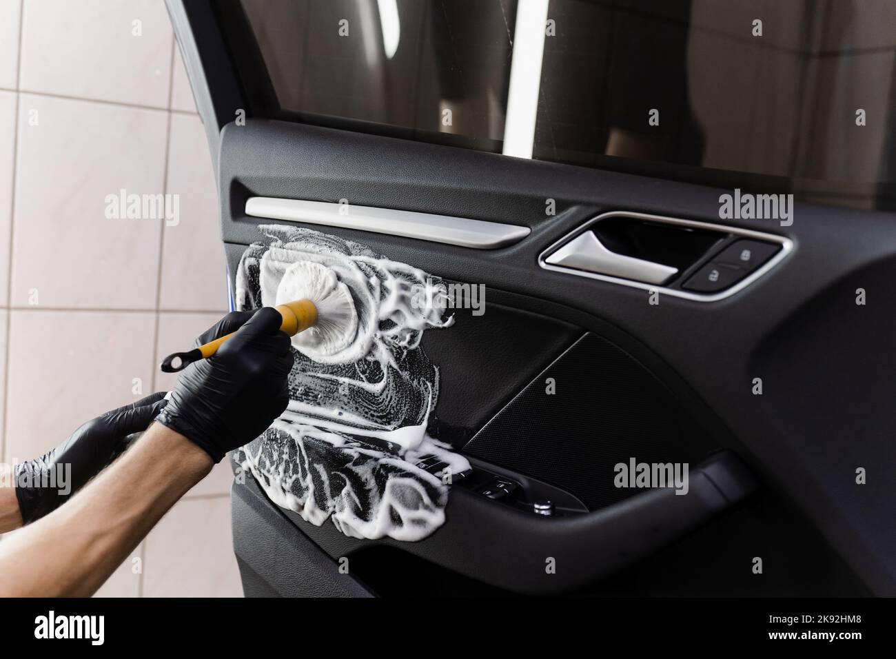 Process of foam and detergent cleaning with brush inside handle of car door. Car detailing