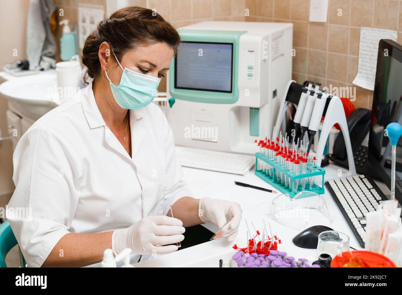 Laboratory assistant works on blood analyzer and makes hematological