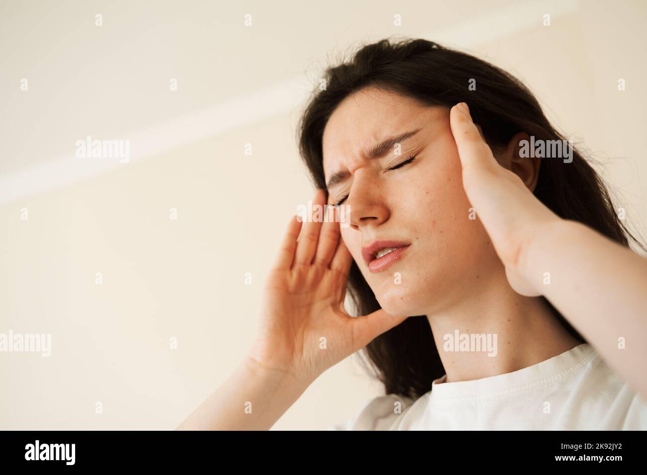 Depressed girl with migraine headache. Sad woman touches temples