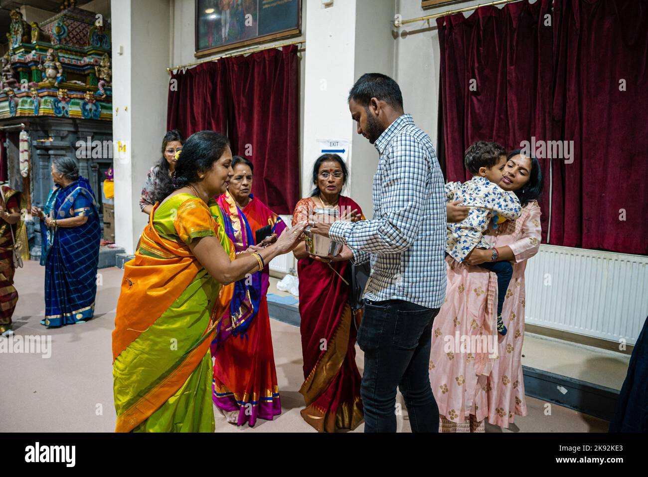 Hindu women symbolically receive blessings from a milk pot that was used to bathe milk onto a deity as it is perceived as a blessed sacrament. Diwali, Deepavali or the Festival of Lights is a five-day celebration observed by millions of Hindus, Sikhs and Jains worldwide. It is a time to celebrate the triumph of good over evil and light over darkness. Devotees visit the Highgate Hill Murugan Temple on the night of Diwali to offer puja or worship rituals for devotional homage to their revered deities. (Photo by Aisha Nazar/SOPA Images/Sipa USA) Stock Photo