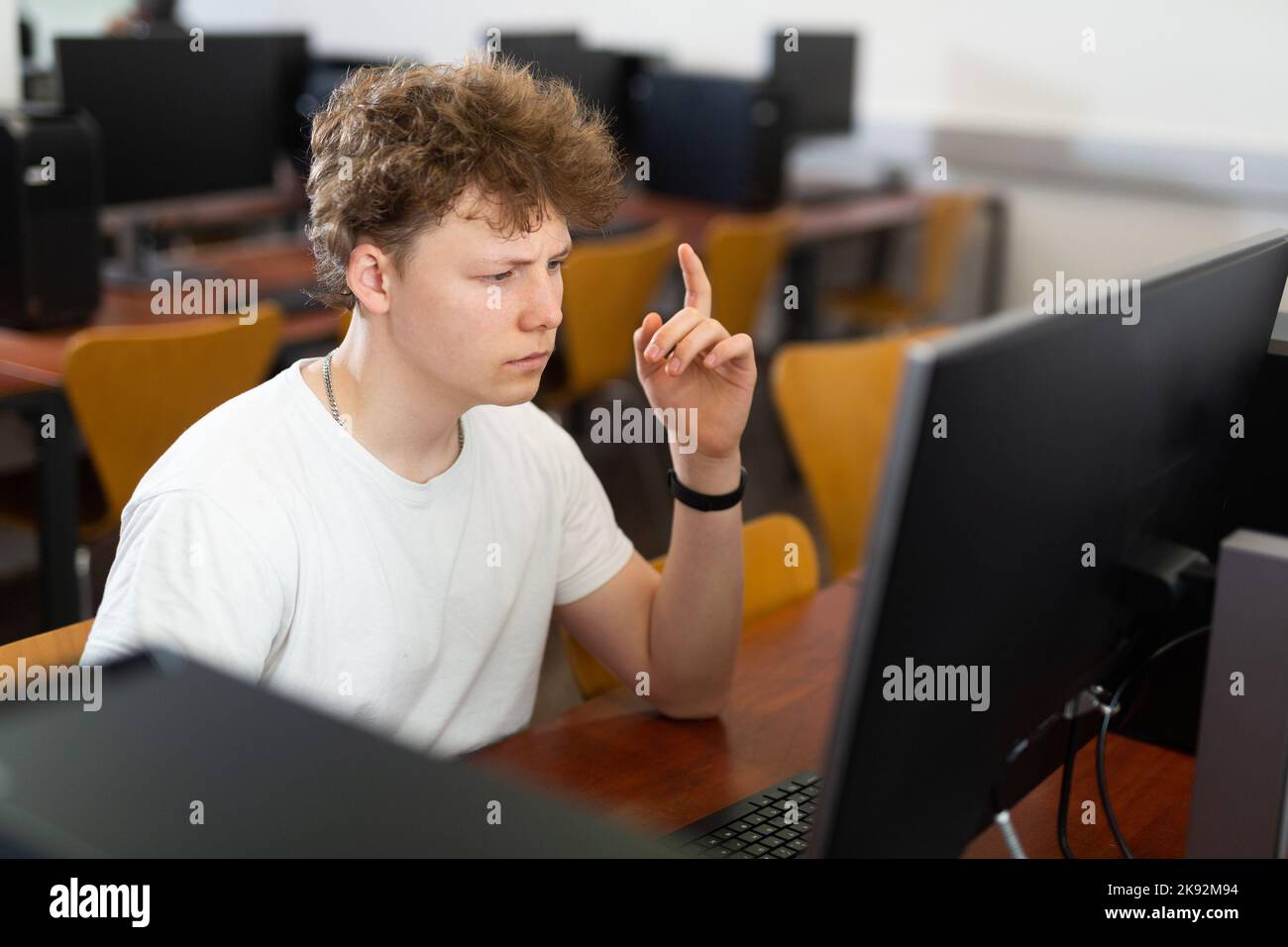 Focused puzzled teenage boy studying in computer lab Stock Photo - Alamy