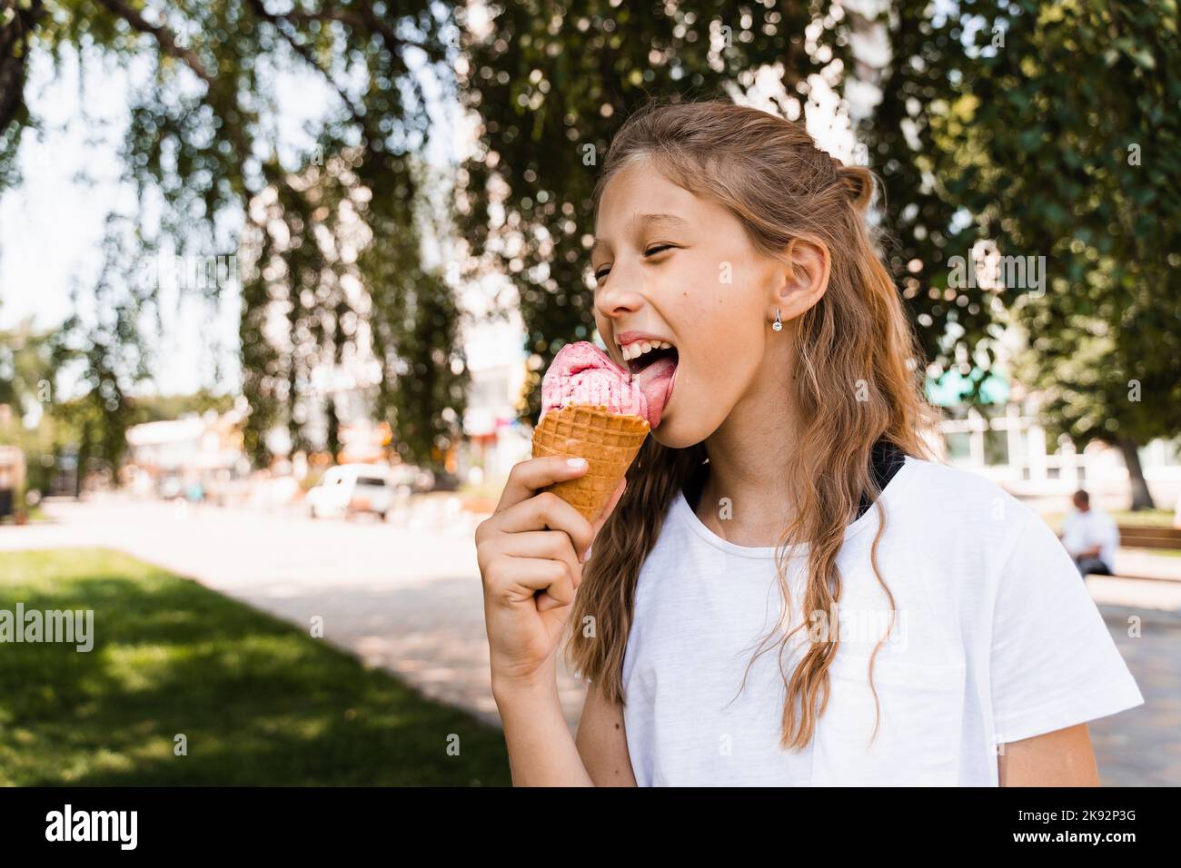 Funny child girl eating ice cream cone in waffle cup. Creative advert for ice cream stand and