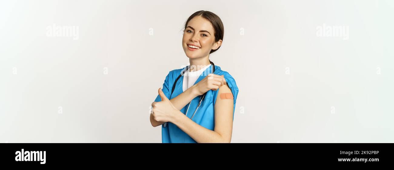 Happy smiling medical worker, doctor or nurse showing her shoulder ...