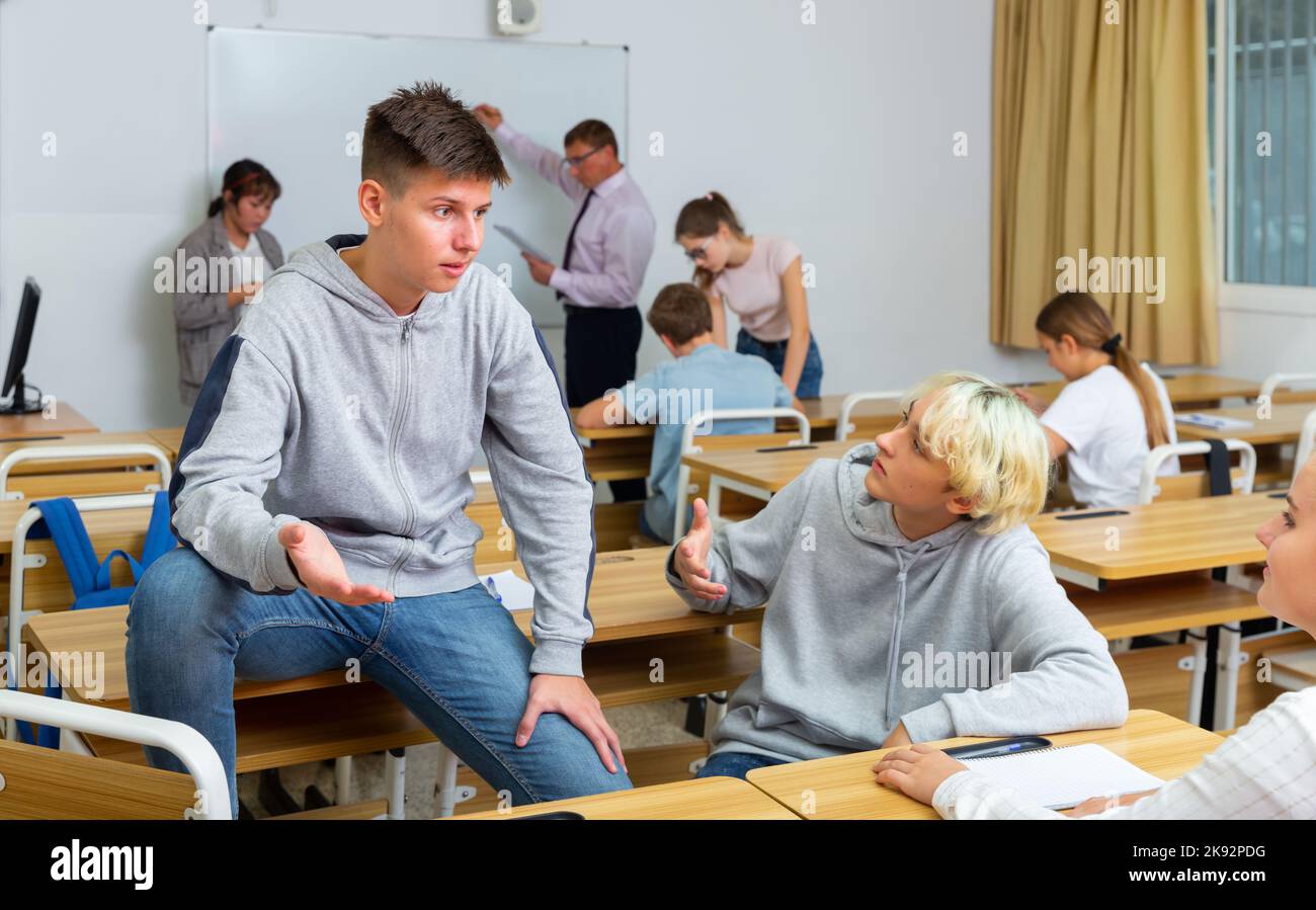 Positive students are talking about homework at desk Stock Photo - Alamy