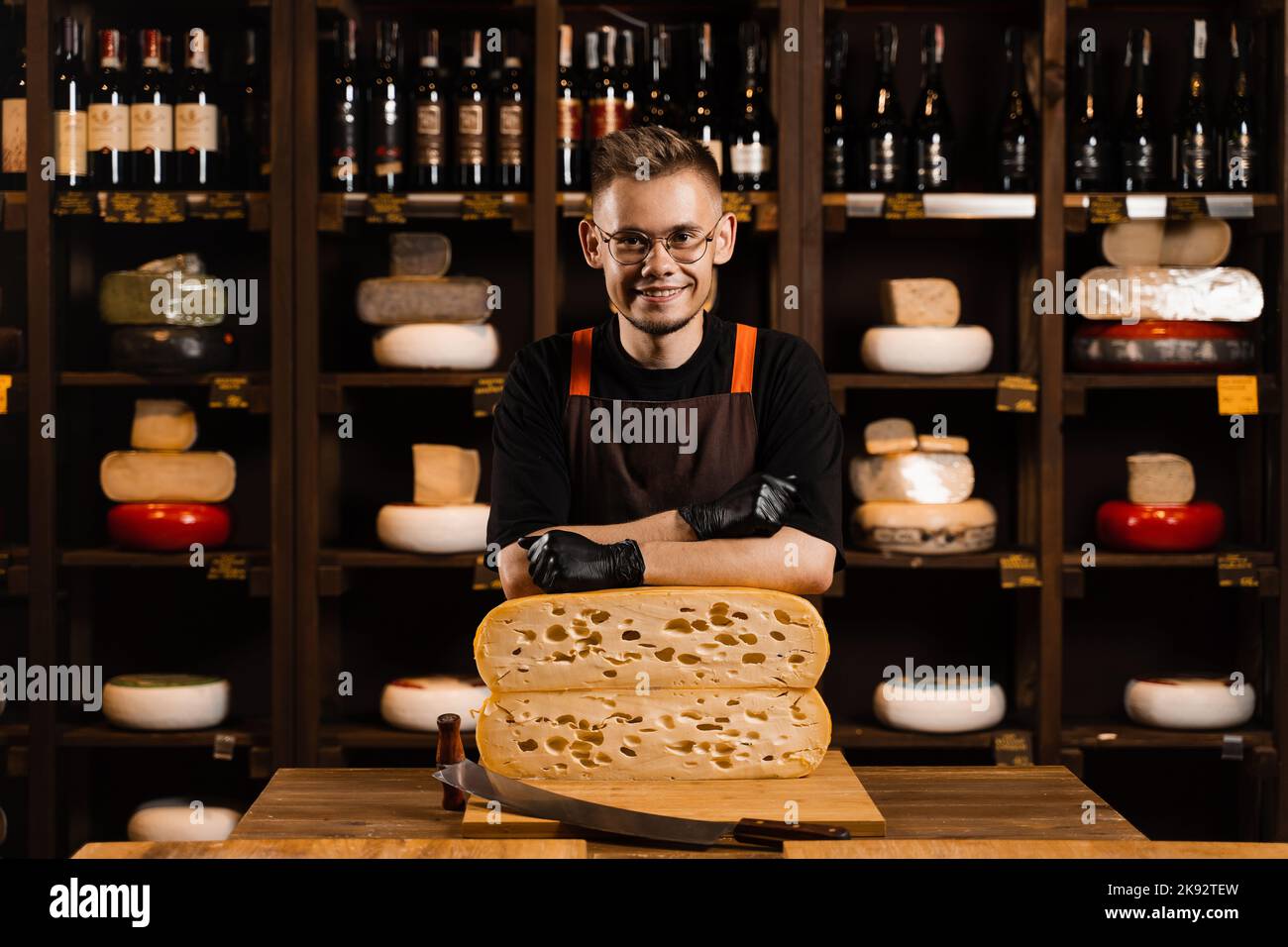 Professional cheese sommelier in food shop. Worker of cheese store with